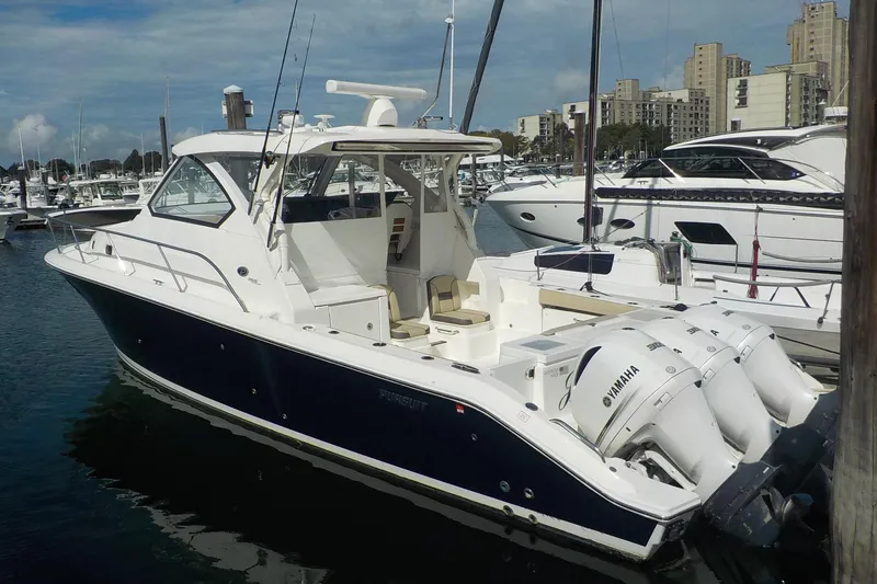 Slide: The Image of 2020 Pursuit OS 355 Offshore boat docked in marina with triple Yamaha engines. - 1