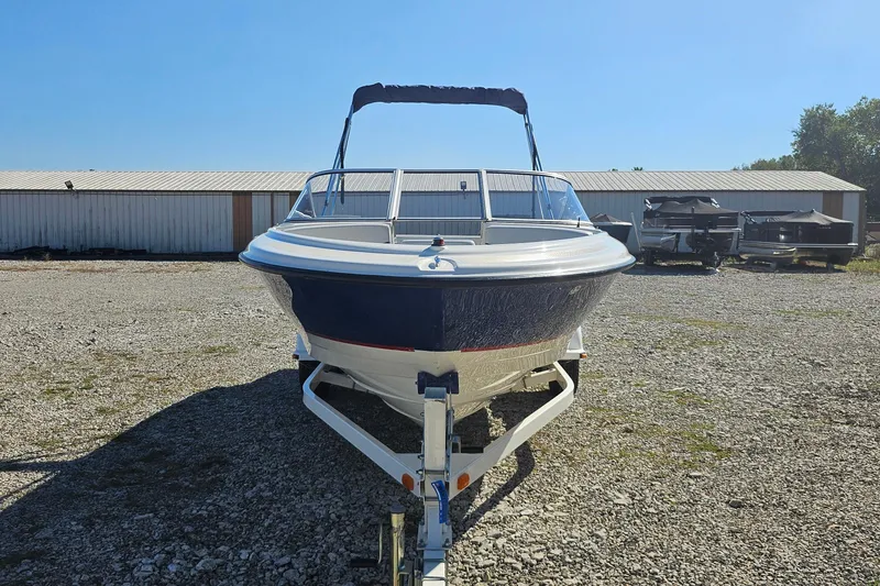 Slide: The Image of 2004 Bayliner 215 Bowrider boat on trailer, parked outdoors under clear sky. - 1