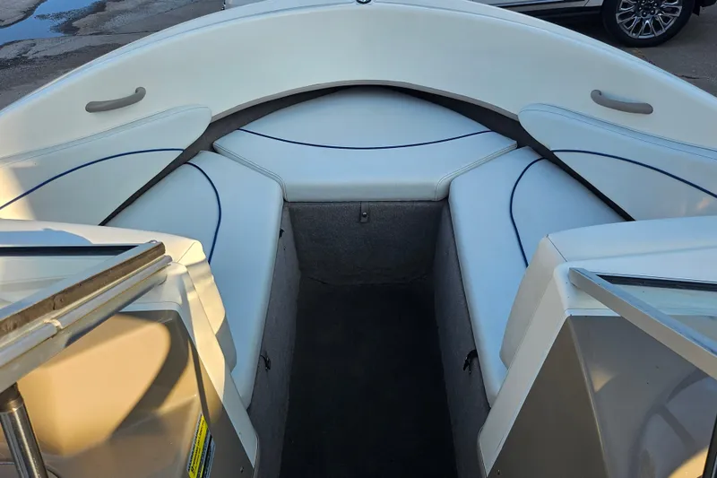 Slide: The Image of 2004 Bayliner 215 Bowrider interior with white cushioned seating and open bow area. - 10