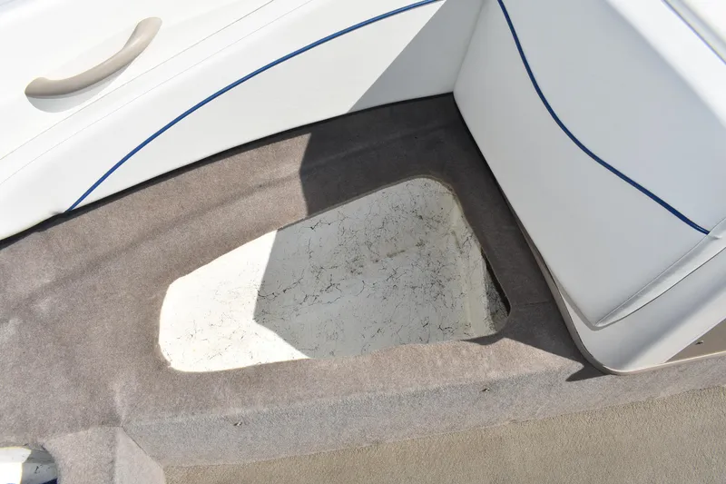 Slide: The Image of 2004 Bayliner 215 Bowrider interior storage compartment with white and gray upholstery. - 12