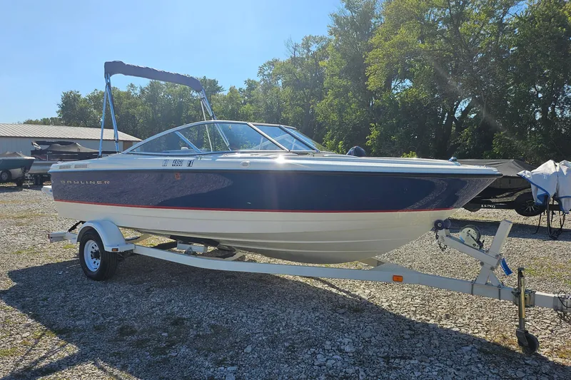 Slide: The Image of 2004 Bayliner 215 Bowrider boat on trailer, parked outdoors on gravel. - 2