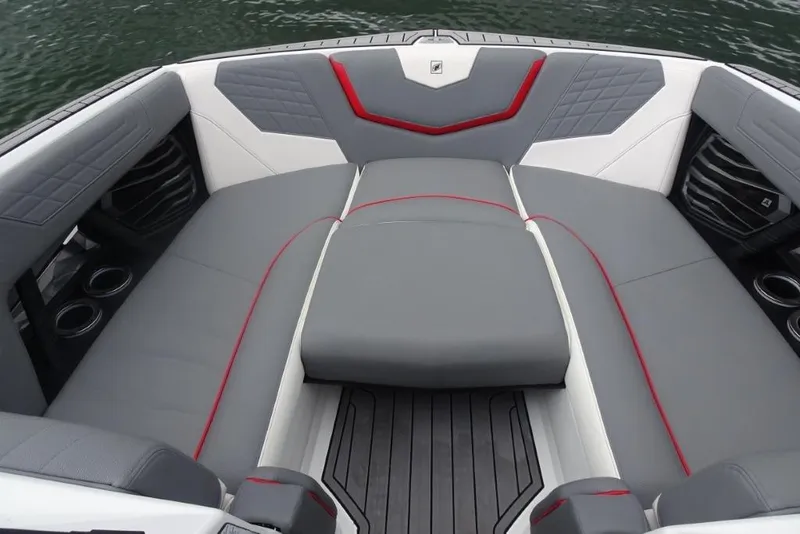 Slide: The Image of 2021 Nautique Super Air Nautique G23 interior with gray and red seating, cup holders, and water backdrop. - 16