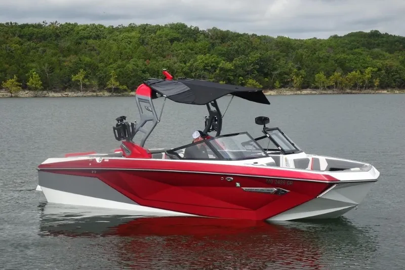 Slide: The Image of 2021 Nautique Super Air Nautique G23 boat on a calm lake with lush green shoreline. - 3