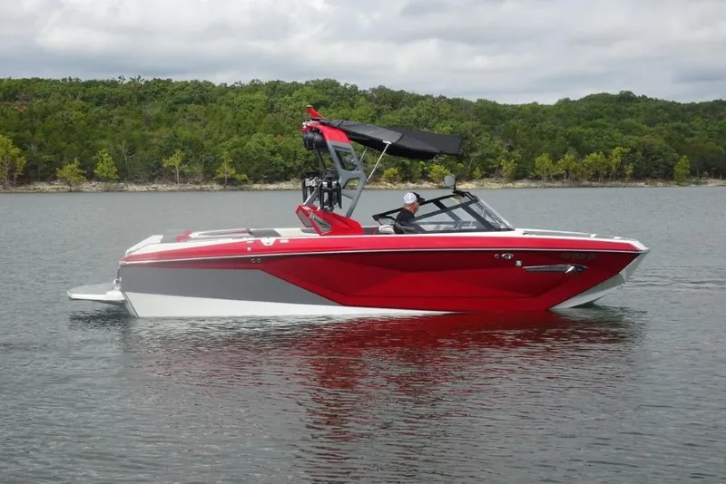 Slide: The Image of 2021 Nautique Super Air Nautique G23 boat on a calm lake with lush green shoreline. - 4