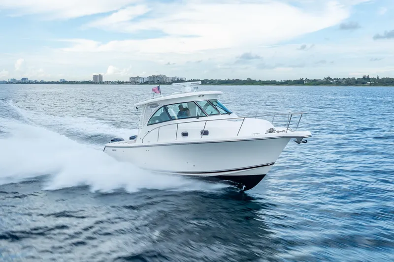 The Image of 2011 Pursuit OS 345 Offshore boat cruising on open water, clear sky background. - 0