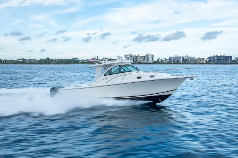 Slide: The Image of 2011 Pursuit OS 345 Offshore boat cruising on open water, cityscape in background. - 17