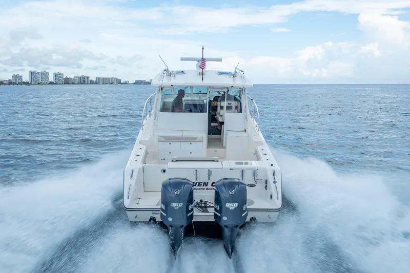 Slide: The Image of 2011 Pursuit OS 345 Offshore boat cruising on open water with city skyline in background. - 20