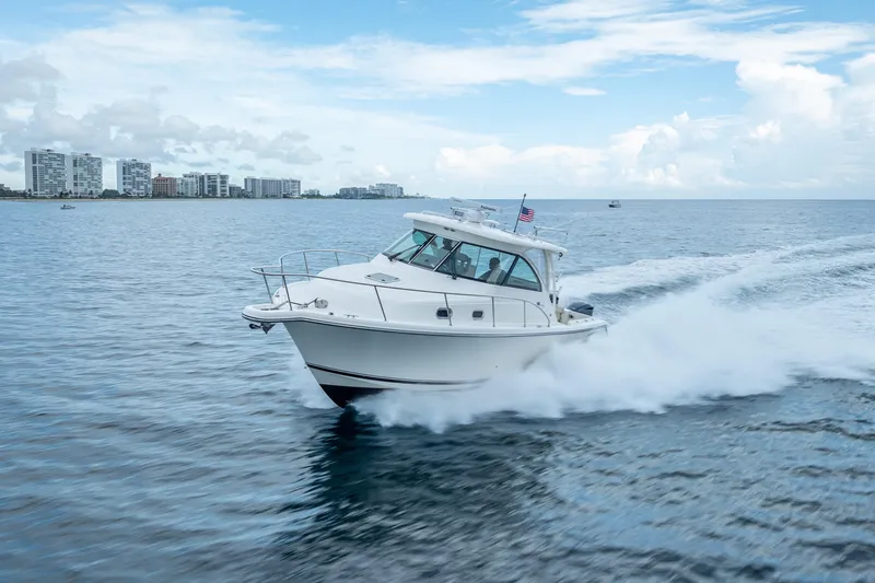 Slide: The Image of 2011 Pursuit OS 345 Offshore boat cruising on open water near city skyline. - 24