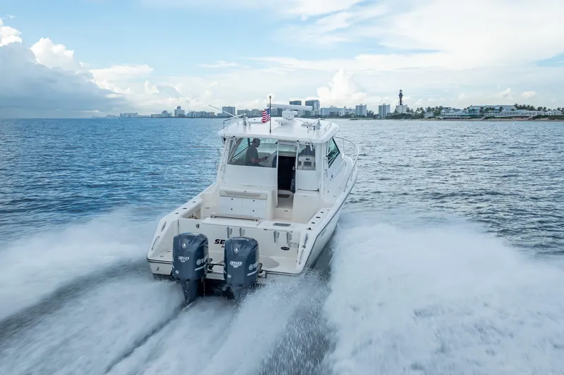 Slide: The Image of 2011 Pursuit OS 345 Offshore boat cruising on open water near city skyline. - 30