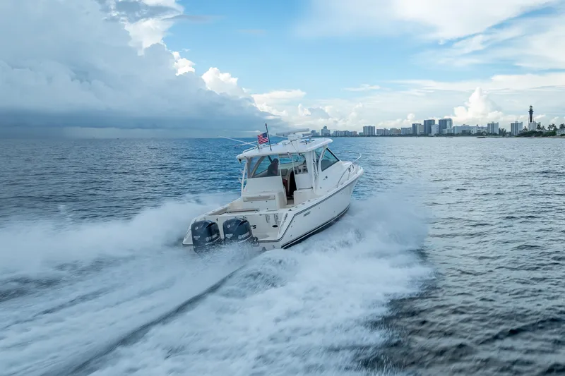 Slide: The Image of 2011 Pursuit OS 345 Offshore boat cruising on open water near city skyline. - 31