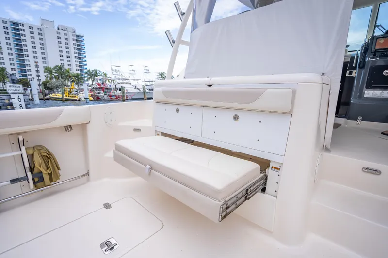Slide: The Image of 2011 Pursuit OS 345 Offshore boat interior with fold-out seating and storage, docked near buildings. - 46