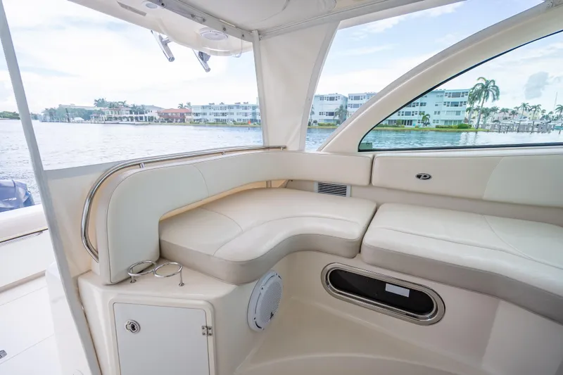 Slide: The Image of 2011 Pursuit OS 345 Offshore boat interior with cream seating, overlooking waterfront homes. - 54