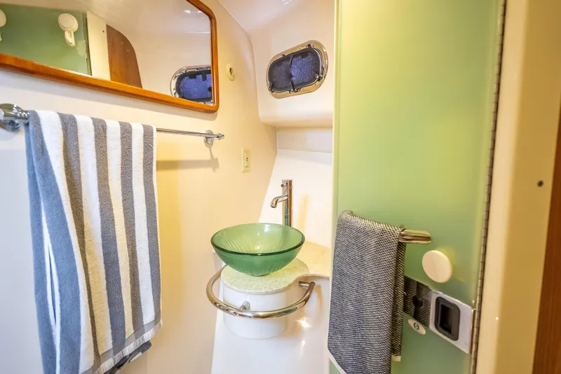 Slide: The Image of 2011 Pursuit OS 345 Offshore bathroom with glass sink and striped towel. - 64