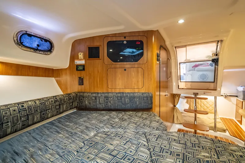 Slide: The Image of 2011 Pursuit OS 345 Offshore cabin interior with patterned seating and wooden accents. - 72