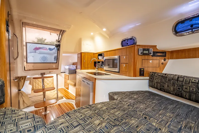Slide: The Image of 2011 Pursuit OS 345 Offshore cabin interior with kitchenette, seating, and wooden accents. - 74