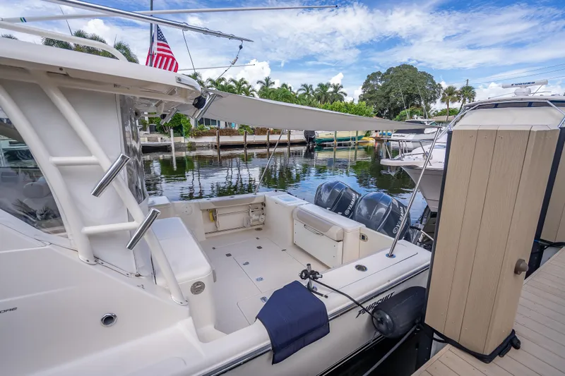 Slide: The Image of 2011 Pursuit OS 345 Offshore boat docked, featuring spacious deck and dual outboard engines. - 79