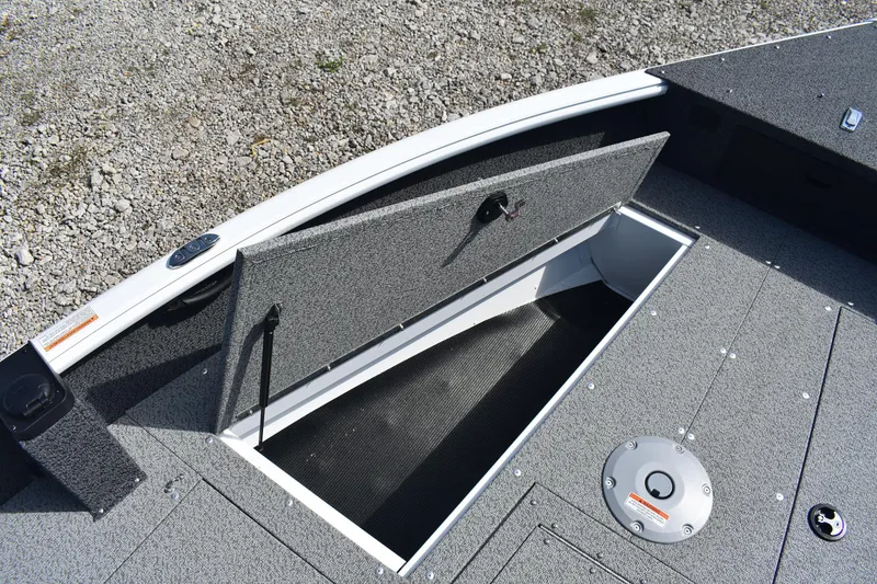 Slide: The Image of 2026 Lund 1800 Explorer SS boat interior with open storage compartment and steering wheel. - 16