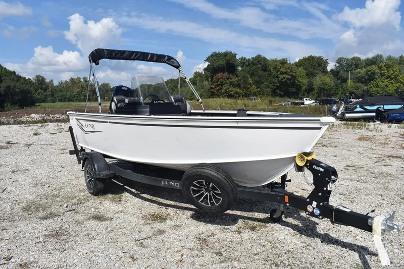 Slide: The Image of 2026 Lund 1800 Explorer SS boat on trailer, parked outdoors under blue sky. - 4
