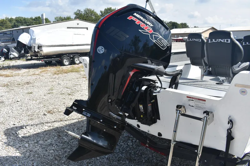 Slide: The Image of 2026 Lund 1800 Explorer SS boat with ladder and outboard motor on gravel. - 7
