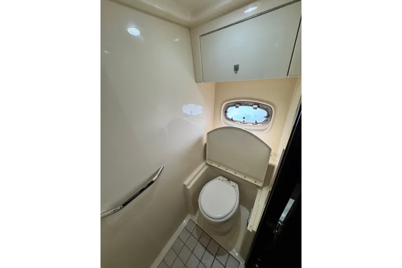 Slide: The Image of 2009 Sea Ray 470 Sundancer bathroom with toilet, cabinet, and porthole window. - 48