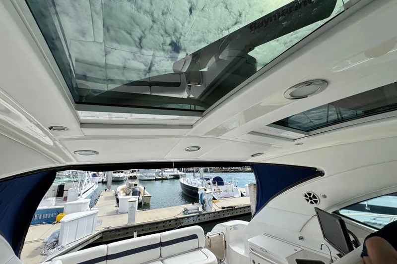 Slide: The Image of Interior view of 2009 Sea Ray 470 Sundancer yacht with open sunroof and marina backdrop. - 87