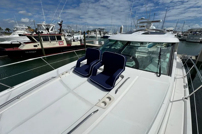 Slide: The Image of 2009 Sea Ray 470 Sundancer yacht with blue chairs on deck, docked in marina. - 93