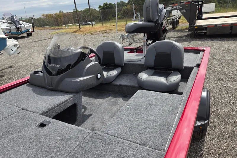 Slide: The Image of 2023 Tracker Pro 170 boat interior with gray seating and red trim, parked outdoors. - 12