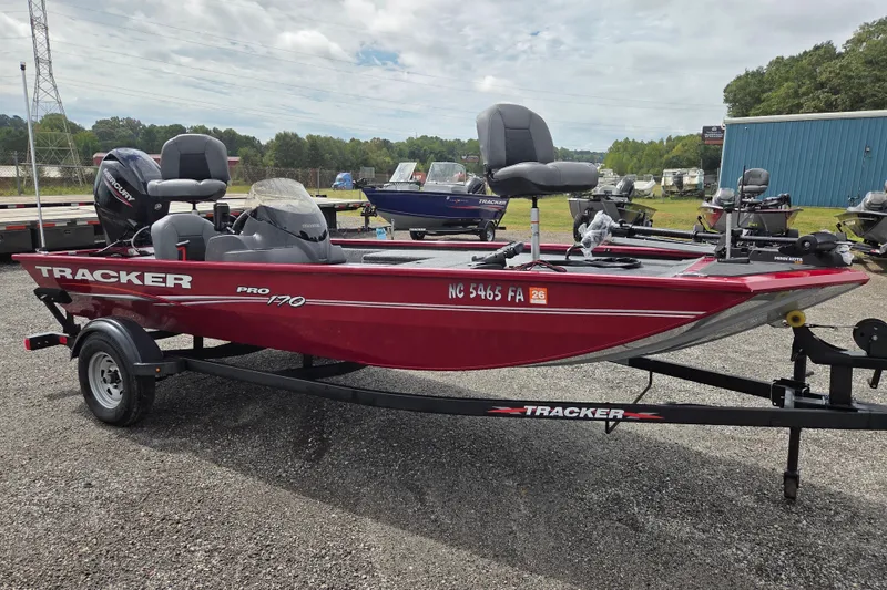 Slide: The Image of 2023 Tracker Pro 170 boat in red on a trailer, parked outdoors. - 2