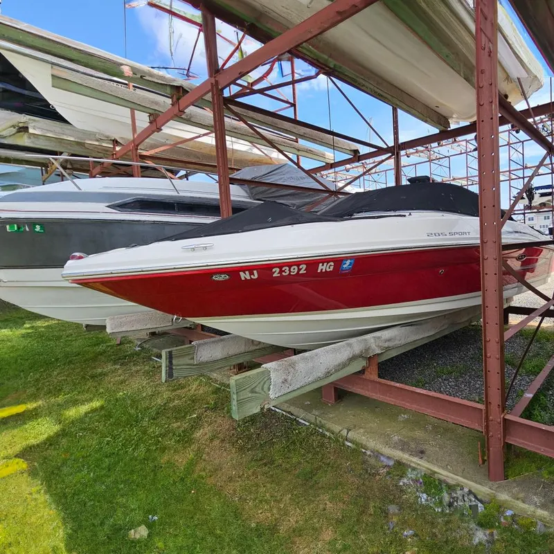 Slide: The Image of 2008 Sea Ray 205 Sport boat in red and white, stored on a rack. - 0