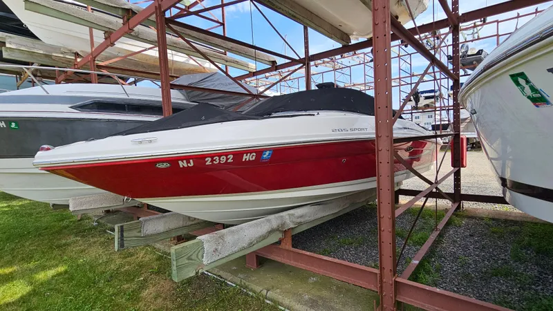 Slide: The Image of 2008 Sea Ray 205 Sport boat in red and white, stored on a rack. - 2