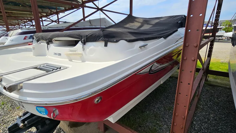 Slide: The Image of 2008 Sea Ray 205 Sport boat with red hull and black cover in storage. - 4