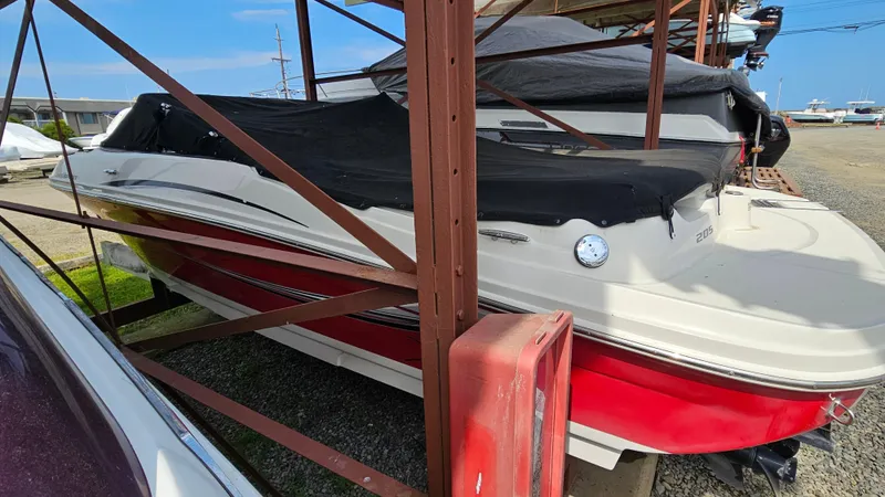 Slide: The Image of 2008 Sea Ray 205 Sport boat with red and white hull, covered and stored outdoors. - 6