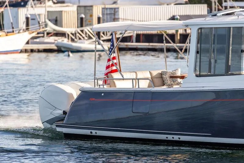 Slide: The Image of 2018 MJM 43z boat cruising with American flag, dockside background. - 11