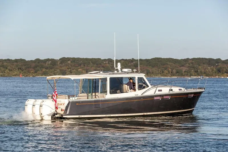 Slide: The Image of 2018 MJM 43z boat cruising on a lake with forested shoreline. - 2