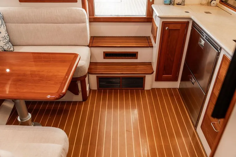 Slide: The Image of Interior of a 2018 MJM 43z yacht featuring a wooden table, seating, and kitchenette. - 32