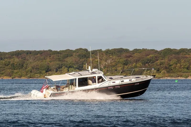 Slide: The Image of 2018 MJM 43z cruising on a scenic lake with lush green shoreline. - 5