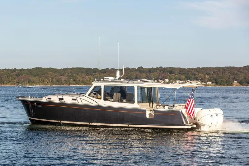Slide: The Image of 2018 MJM 43z boat cruising on a serene lake with forested shoreline. - 7