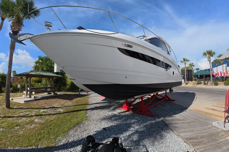 Slide: The Image of 2021 Sea Ray Sundancer 350 Coupe on display, elevated on red stands, with palm trees in the background. - 4