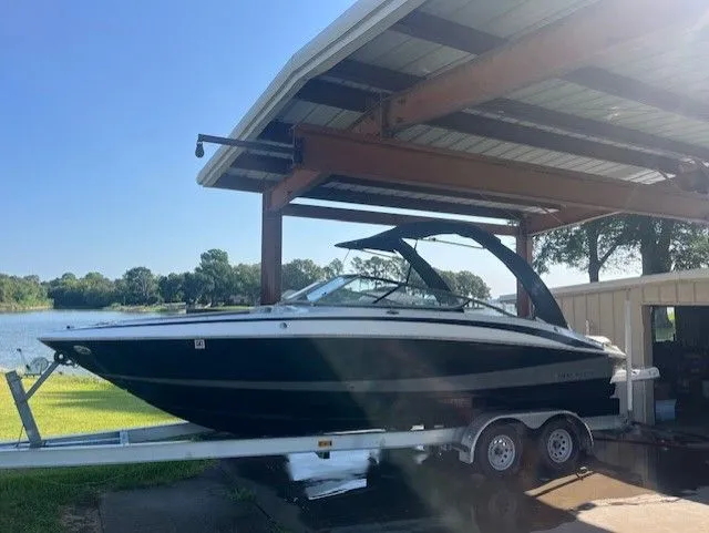 The Image of 2010 Regal 2500 boat on trailer under shelter by lake. - 0