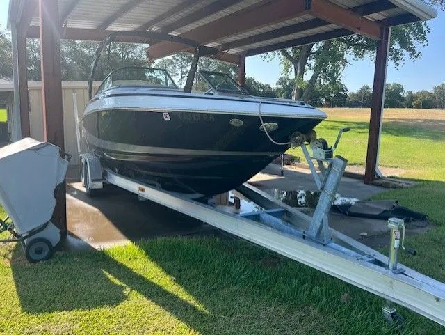 Slide: The Image of 2010 Regal 2500 boat on trailer under metal canopy, parked on grass. - 3