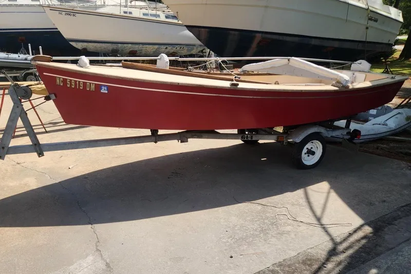 The Image of Red 1986 Point Jude 16 sailboat on trailer, parked in a marina. - 0