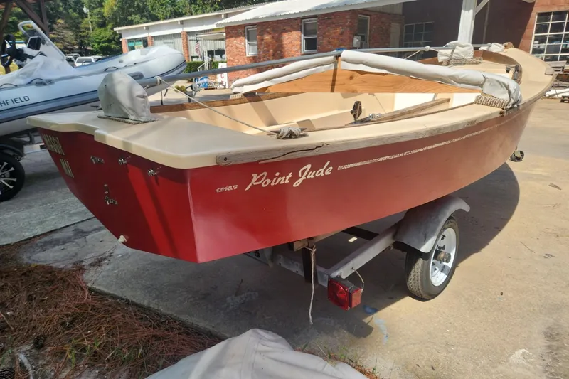 Slide: The Image of 1986 Point Jude 16 sailboat on trailer, red hull, outdoor setting. - 2