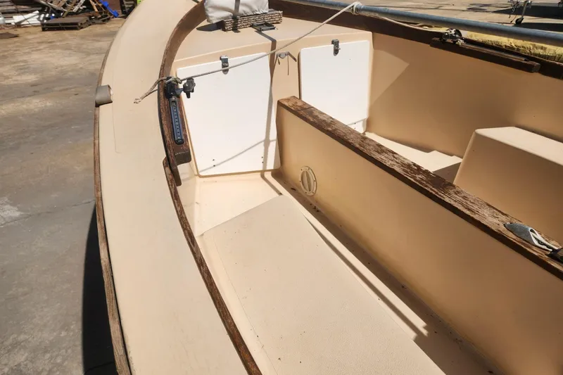Slide: The Image of 1986 Point Jude 16 sailboat interior with wooden trim and seating area. - 5