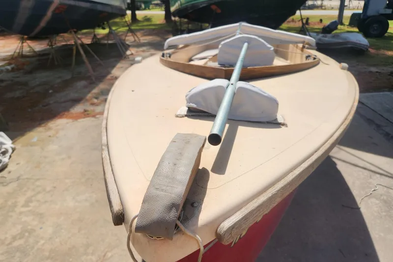 Slide: The Image of 1986 Point Jude 16 sailboat on land, showing deck and mast, in a sunny boatyard. - 7