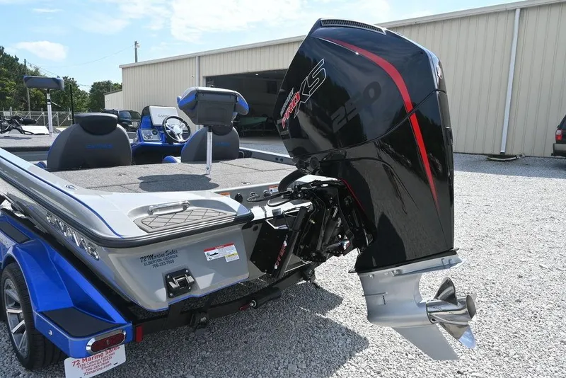 Slide: The Image of 2026 Caymas CX21 boat with powerful outboard motor, parked on gravel near a warehouse. - 11