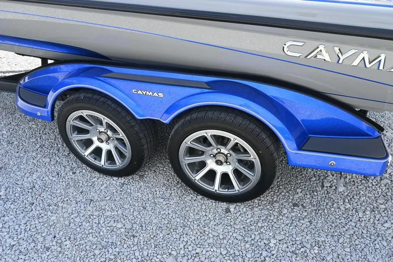 Slide: The Image of 2026 Caymas CX21 boat trailer with blue fenders and dual wheels on gravel. - 12