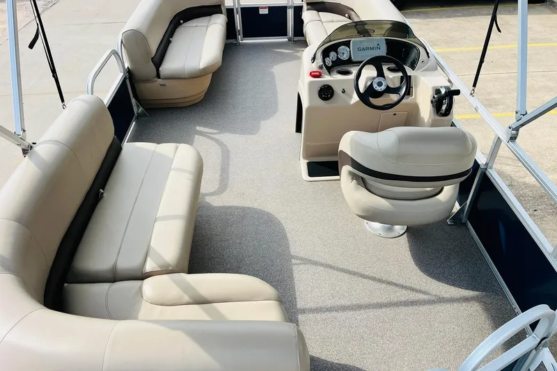 Slide: The Image of 2019 Sun Tracker Party Barge 18 DLX interior with beige seating and steering console. - 10