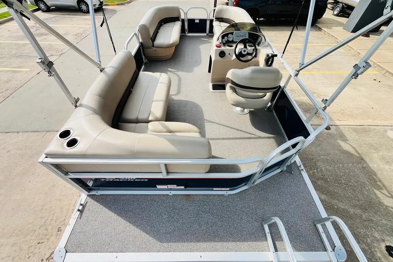 Slide: The Image of 2019 Sun Tracker Party Barge 18 DLX interior with beige seating and steering console. - 11