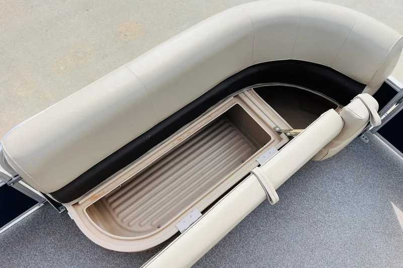 Slide: The Image of Sun Tracker Party Barge 18 DLX 2019, open storage compartment under beige seating. - 16