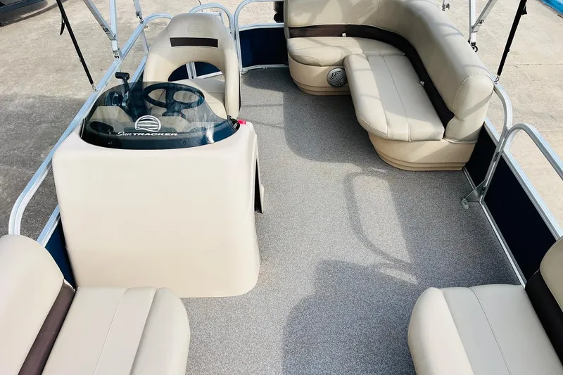 Slide: The Image of 2019 Sun Tracker Party Barge 18 DLX interior with beige seating and steering console. - 21